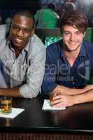 Portrait of two men having whiskey at bar counter