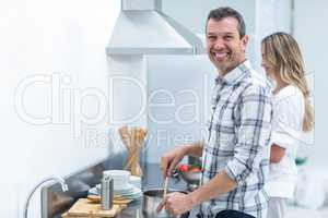 Man helping pregnant woman prepare food