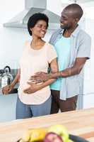 Pregnant couple embracing in kitchen