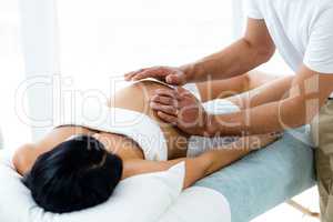 Pregnant woman receiving a stomach massage from masseur