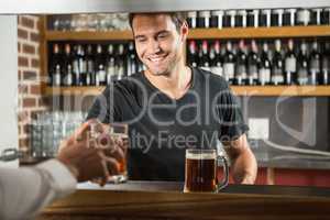 Handsome bar tender giving a pint to customer
