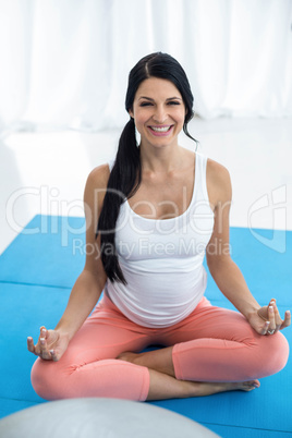 Pregnant woman meditating on mat