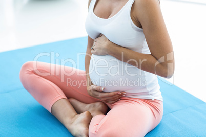 Pregnant woman touching her stomach while exercising