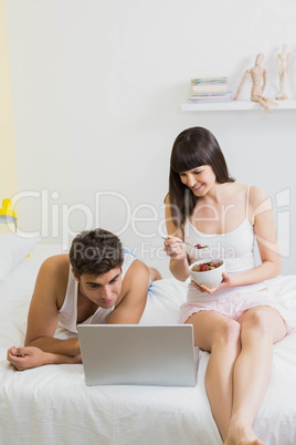 Young couple looking at laptop on bed