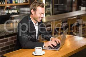 Handsome man using laptop and having a coffee