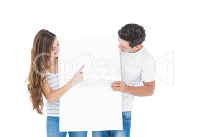 Happy couple pointing a white poster