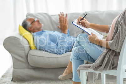 Female doctor writing on clipboard while consulting a man