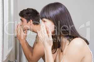 Young couple looking at face in mirror