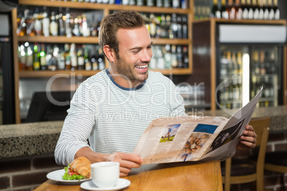 Handsome man reading newspaper and having a coffee