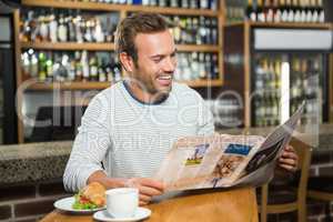 Handsome man reading newspaper and having a coffee