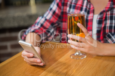Pretty woman using smartphone and having a beer