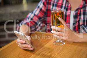 Pretty woman using smartphone and having a beer