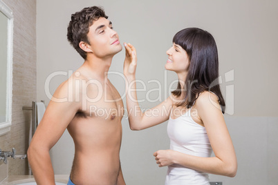 Woman applying moisturizer on mans face