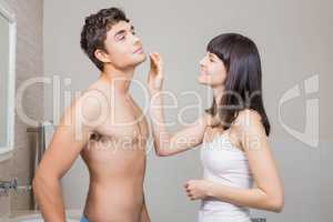 Woman applying moisturizer on mans face
