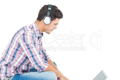 Man with headphones sitting on the floor using laptop