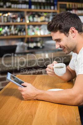 Handsome man using tablet and having coffee