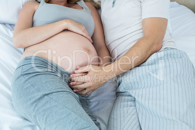 Expecting couple lying on bed and chatting