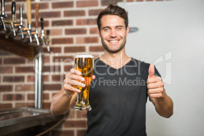 Handsome man holding a pint of beer with thumbs up