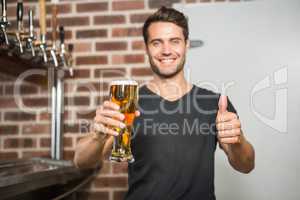 Handsome man holding a pint of beer with thumbs up