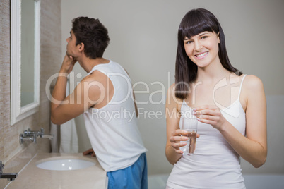 Beautiful woman holding pill and glass of water