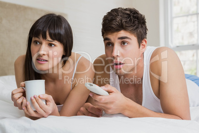 Young couple watching television together on bed