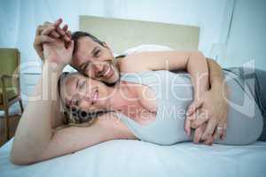 Expecting couple lying on bed and chatting