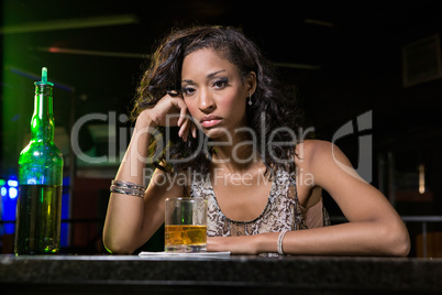 Depressed woman having whiskey at bar counter