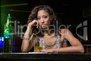 Depressed woman having whiskey at bar counter