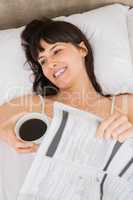 Woman lying on bed with cup of coffee