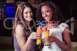Young women toasting cocktail glasses at bar counter