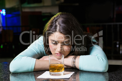 Depressed woman having whiskey at bar counter