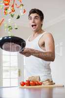 Young man tossing vegetables in frying pan