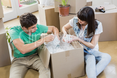 Young couple unpacking carton boxes in their new house