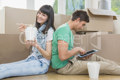 Young couple eating noodle and using digital tablet