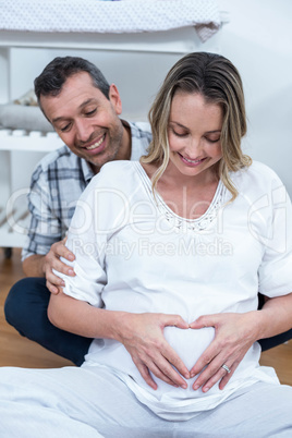 Couple making a heart shape on belly