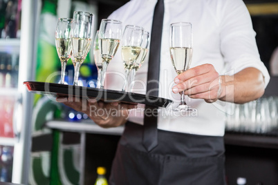 Mid section of bartender serving champagne