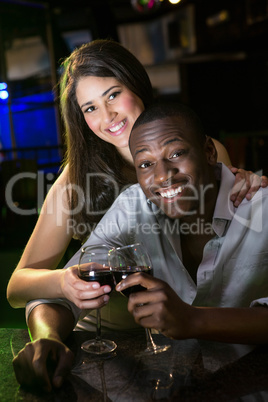 Portrait of couple smiling and toasting their wine glasses at ba Portrait of couple smiling and toasting their wine glasses at ba