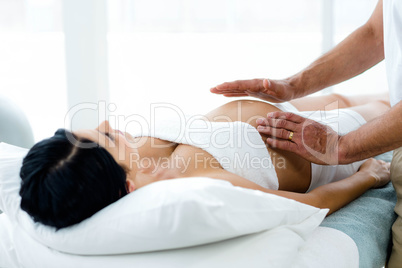 Pregnant woman receiving a stomach massage from masseur