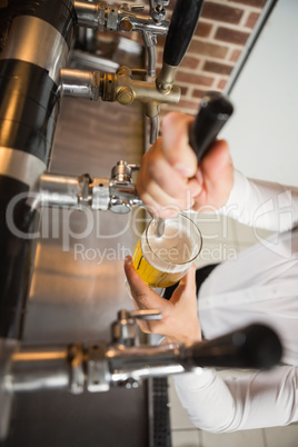 Handsome barman pouring a pint of beer