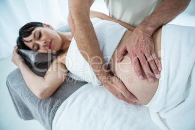 Pregnant woman receiving a stomach massage from masseur