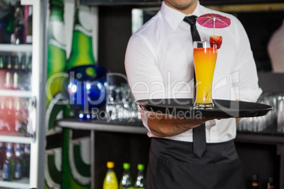 Mid section of bartender serving cocktail