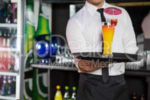 Mid section of bartender serving cocktail