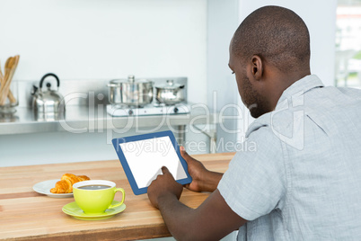 Man using digital tablet while having breakfast