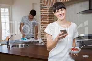 Woman using mobile phone while having breakfast cereals