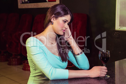 Thoughtful woman having red wine at bar counter