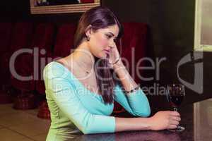 Thoughtful woman having red wine at bar counter