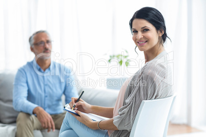 Female doctor writing on clipboard while consulting a man