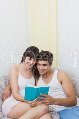 Young couple reading a novel on sofa