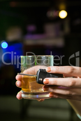 Woman holding a glass of whiskey and car keys