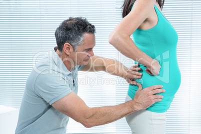 Physiotherapist checking pregnant womans lower back